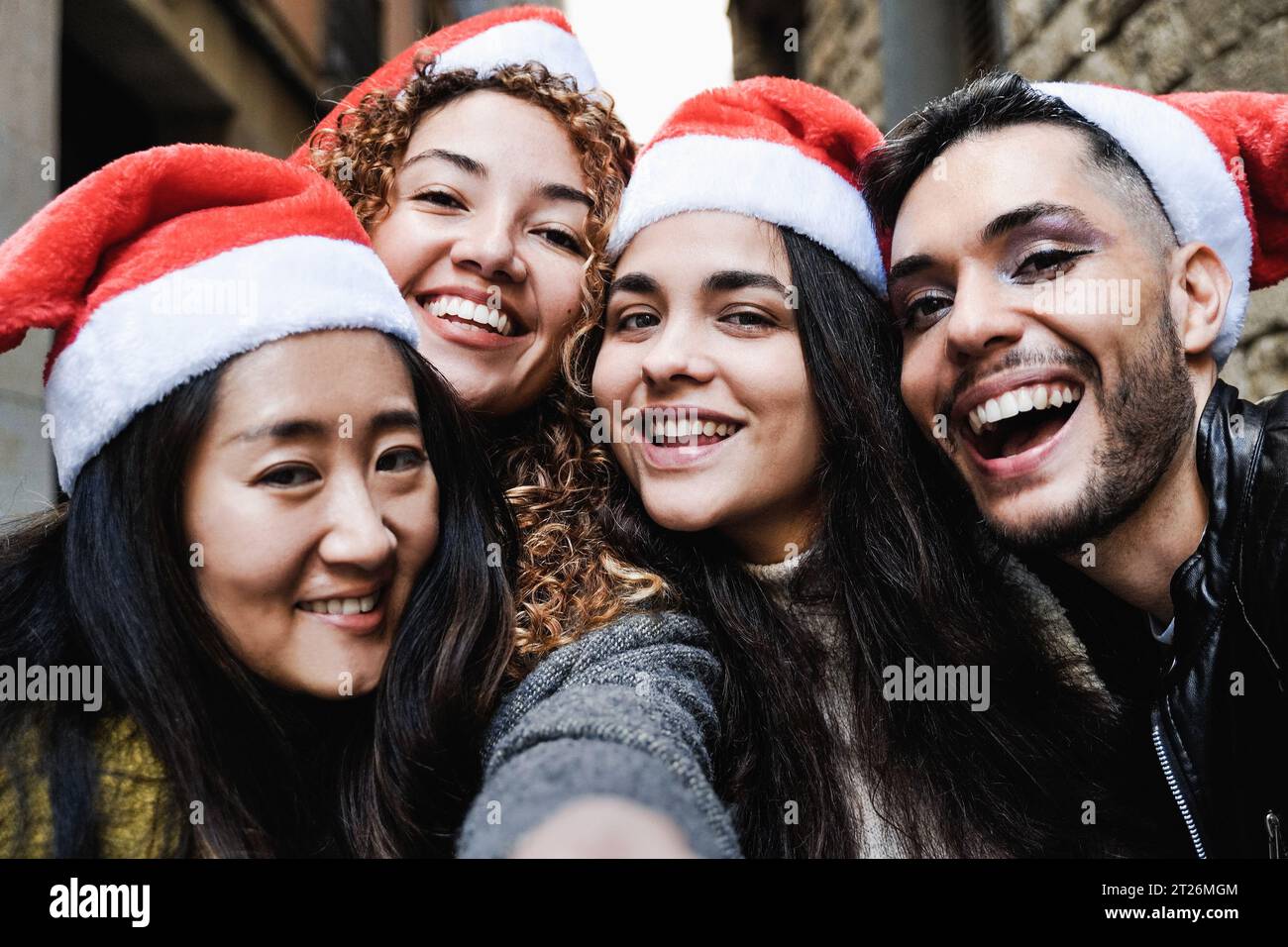 Eine Gruppe von Freunden, die Spaß haben, Weihnachten auf der Straße der Stadt zu feiern - Junge Leute machen Selfie-Fotos mit Weihnachtsmannmützen während der Ferien Stockfoto