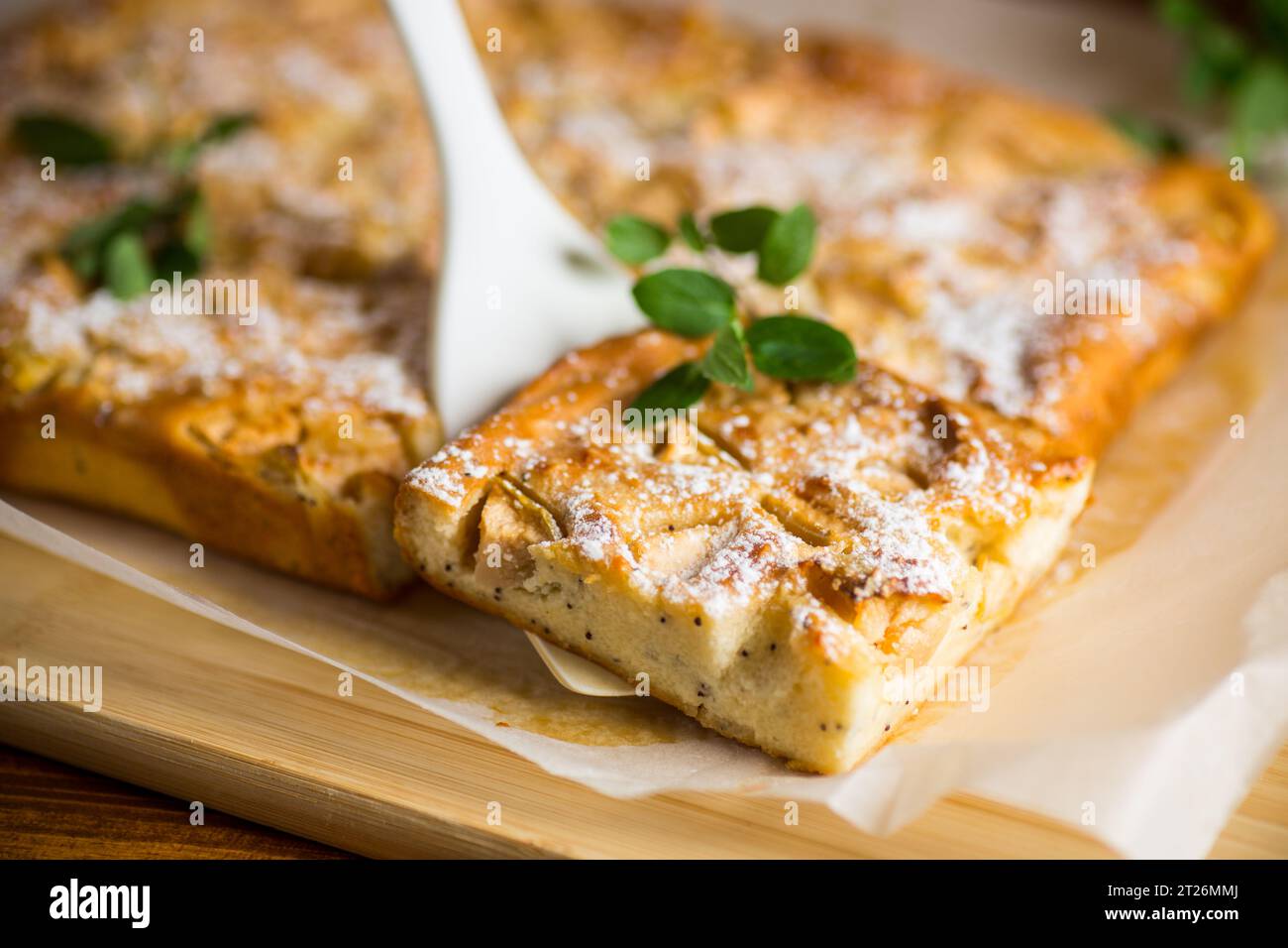 Zubereiteter Quark-Grieskuchen mit Quitte innen und mit Puderzucker auf einem Holzbrett bedeckt. Stockfoto
