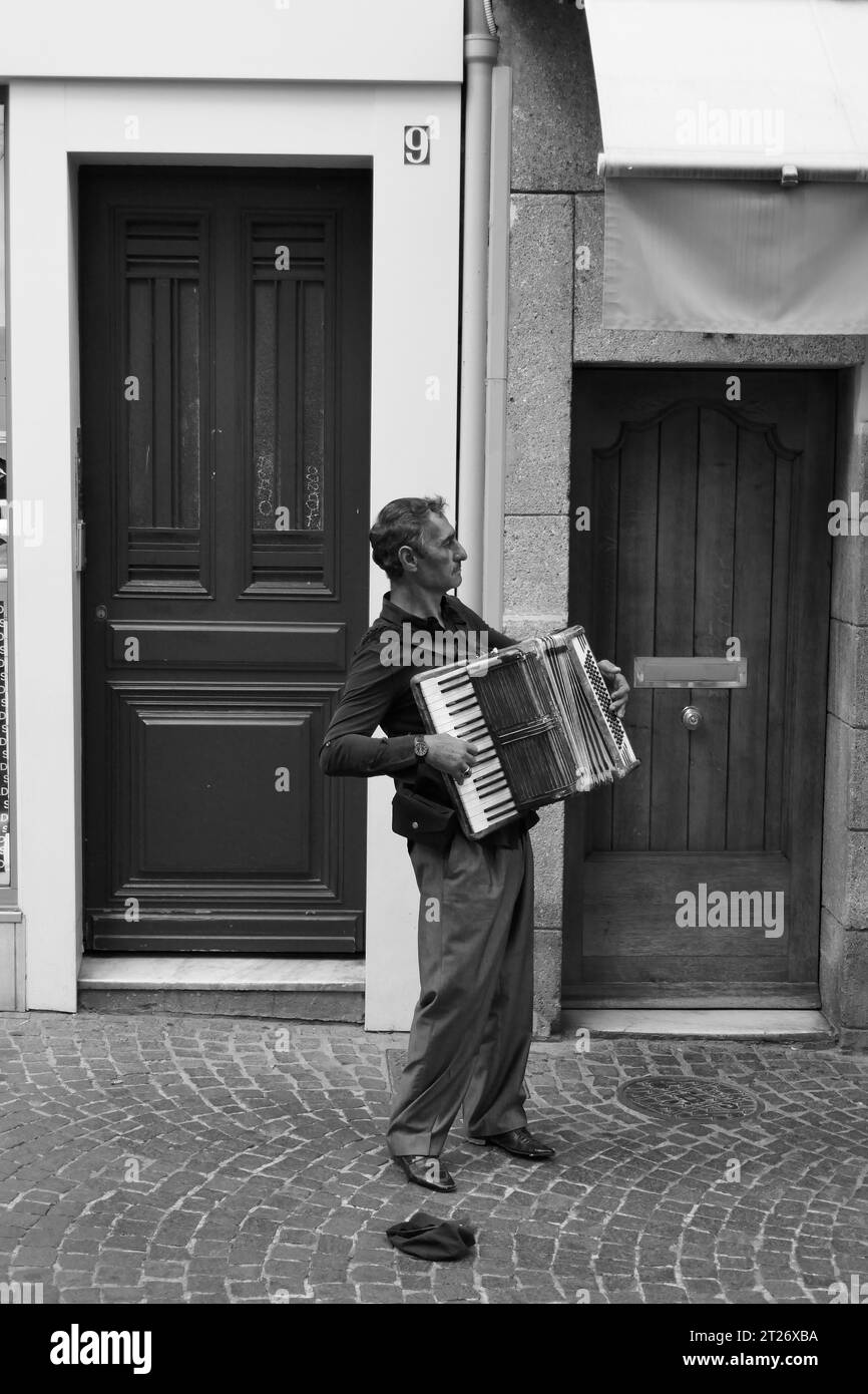 Straßenmusiker spielt Akkordeon in Schwarz-weiß-Urban-Szene in der Altstadt von Antibes, Frankreich Stockfoto