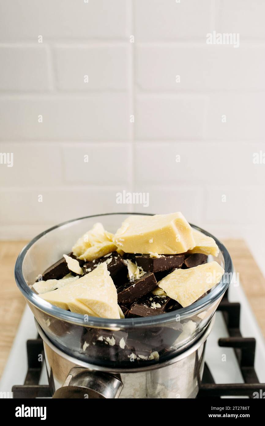Schokolade und Kakaobutter schmelzen im Dampf auf einem Teller. Nahaufnahme. Vertikaler Rahmen. Stockfoto