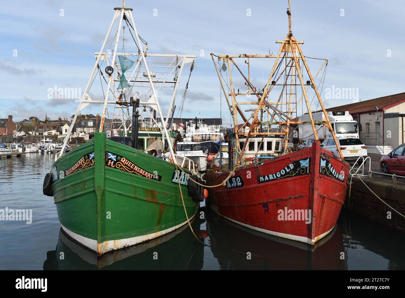 Ein grünes Boot (Queensberry BA156) und ein rotes Boot (Marigold A52) liegen im Arbroath Harbour an der Ostküste Schottlands. Stockfoto