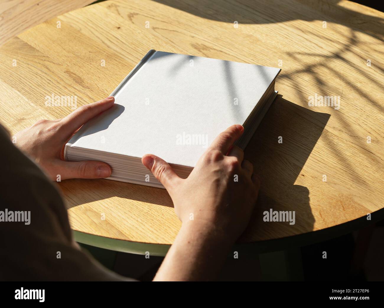 Hand mit sauberem Buchcover Mockup auf Holztisch Stockfoto