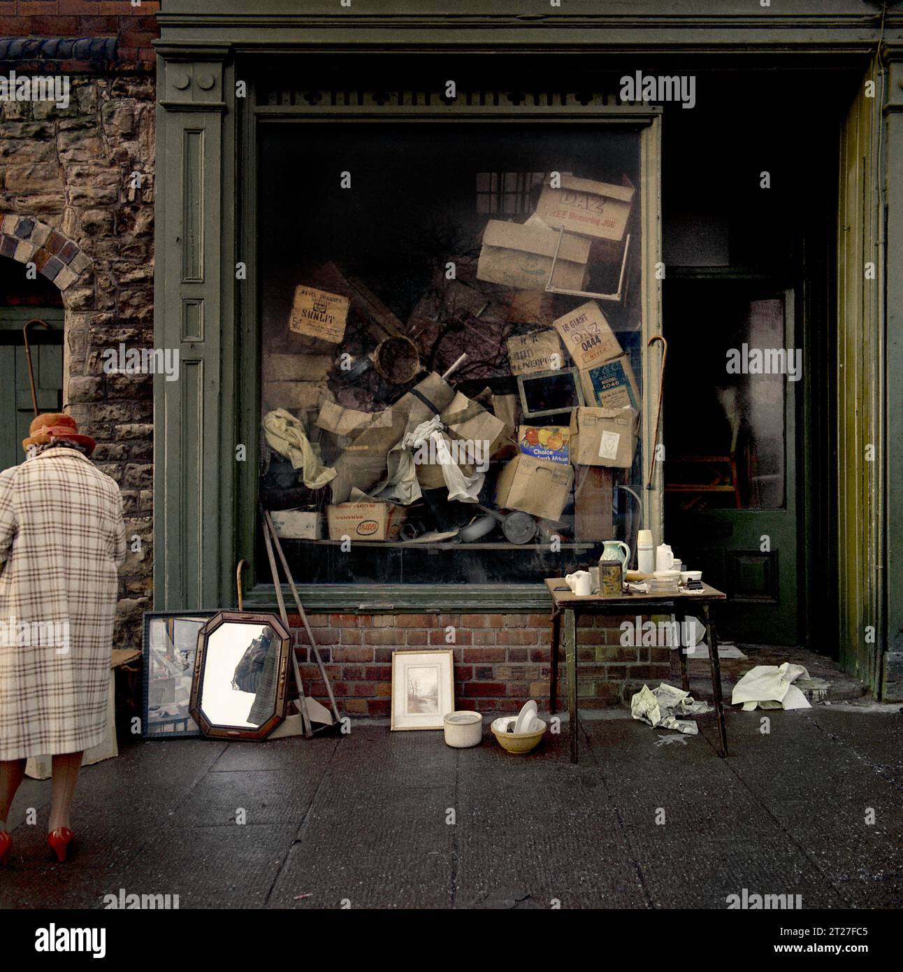 Die ältere Dame stand vor einem Secondhand-Laden neben dem Sneinton Market während der Slumräumung und des Abbruchs von St Ann's, Nottingham. 1969-1972 Stockfoto