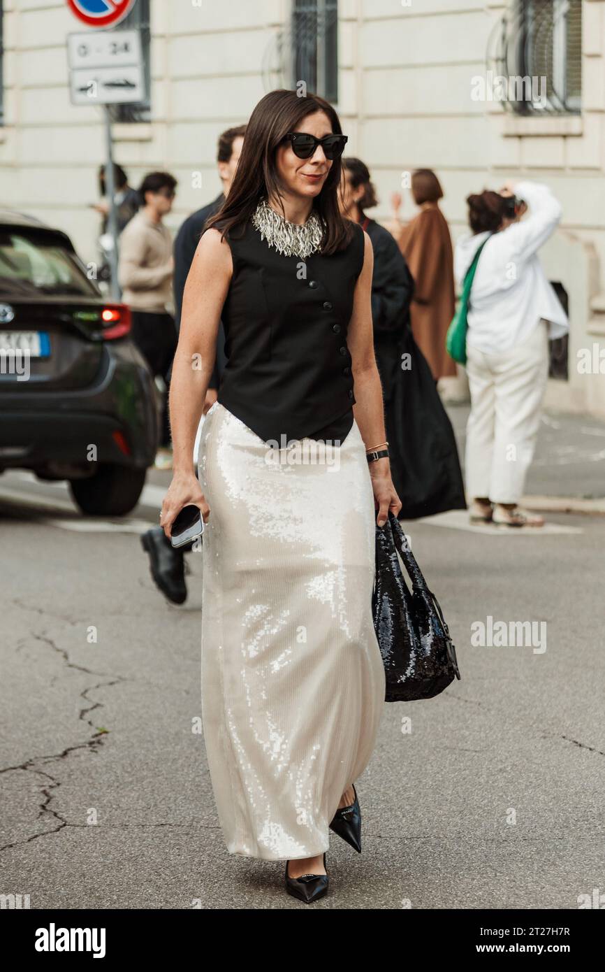 Ein Gast trägt eine weiße Halskette, eine schwarze Button-down-Bluse, einen weißen langen Rock mit Pailletten und eine schwarze Tasche, die vor der MAX MARA Show während der Mailänder Fashion Week zu sehen ist Stockfoto