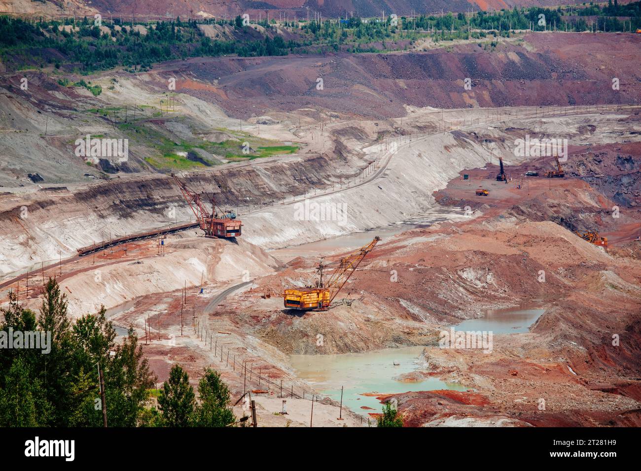 Hydraulikbagger und Kipplaster, die im Tagebau in Bergbau- und Verarbeitungsanlagen Erdbewegungsarbeiten durchführen. Stockfoto