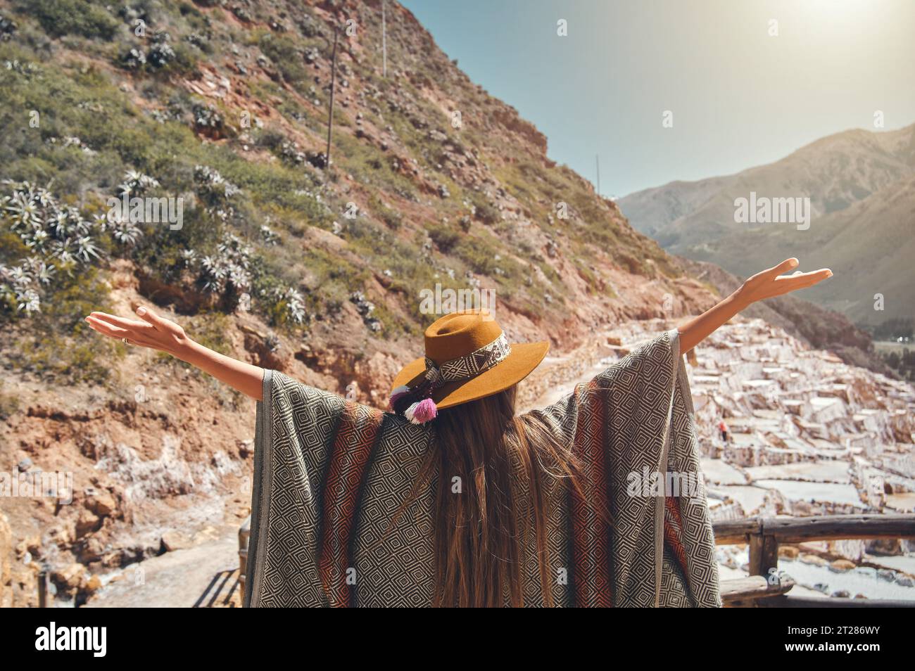 Weibliche Touristen mit in Hut und Poncho, die Maras Salzminen, Peru erkunden. Reise- und Fernweh-Konzept. Stockfoto
