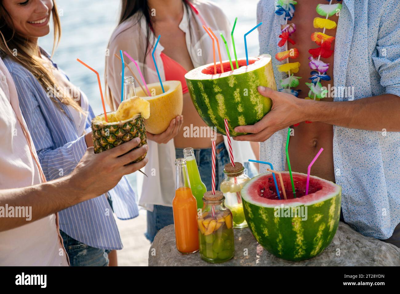 Trendige Gruppe von Freunden, die Cocktails auf der Party trinken. Junge Leute, die Spaß im Luxusresort haben. Stockfoto