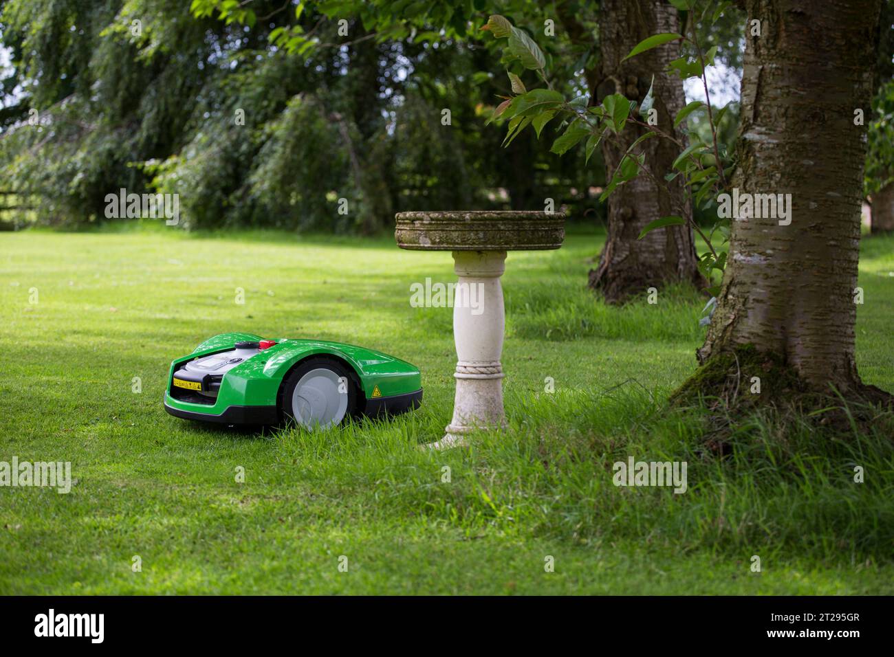 Ein automatisierter Rasenmäher, der Hindernisse in einem Garten in Großbritannien überwindet. Stockfoto