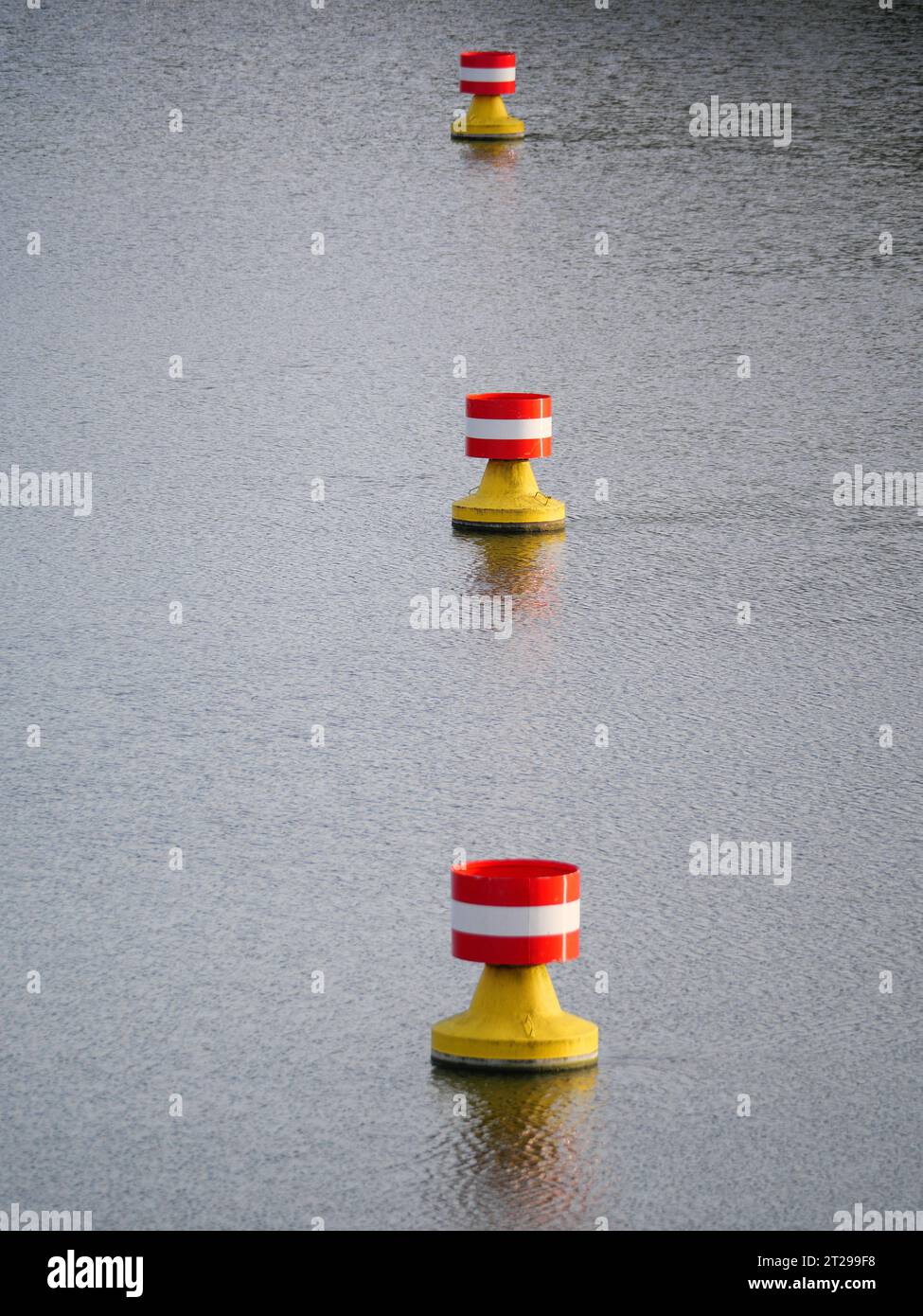 Rot-gelbe, weiße Bojen treiben in der Strömung auf der Wasseroberfläche eines Flusses Stockfoto