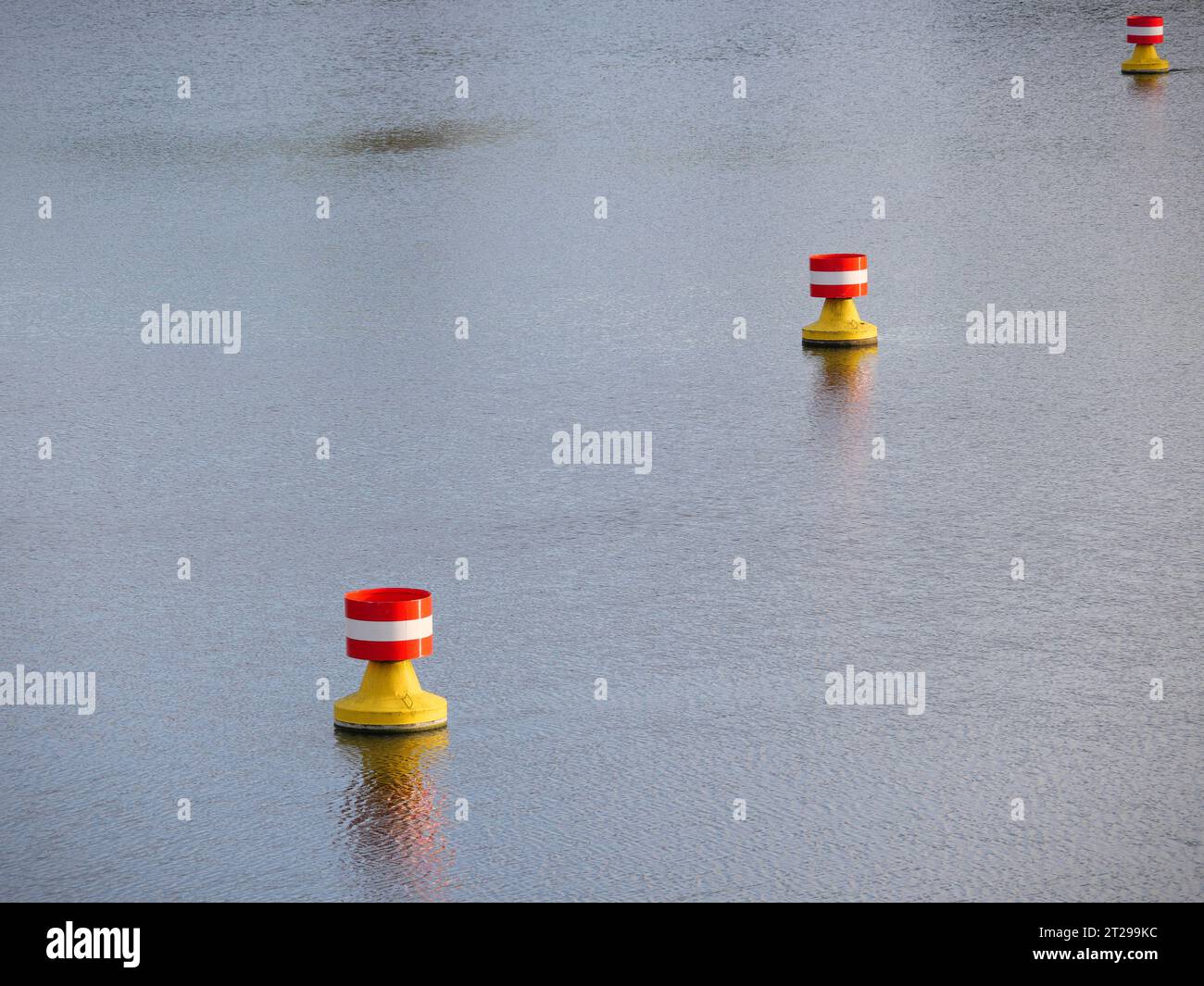 Rot-gelbe, weiße Bojen treiben in der Strömung auf der Wasseroberfläche eines Flusses Stockfoto