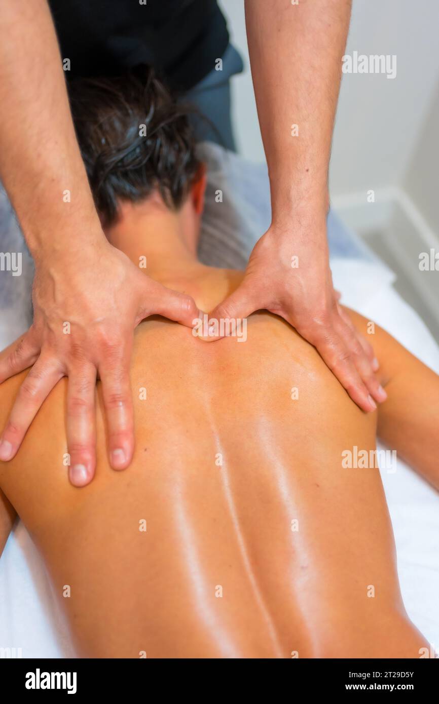 Physiotherapeutische Massage bei einer nicht erkennbaren Frau, die auf einer Liege auf ihrem Rücken liegt Stockfoto