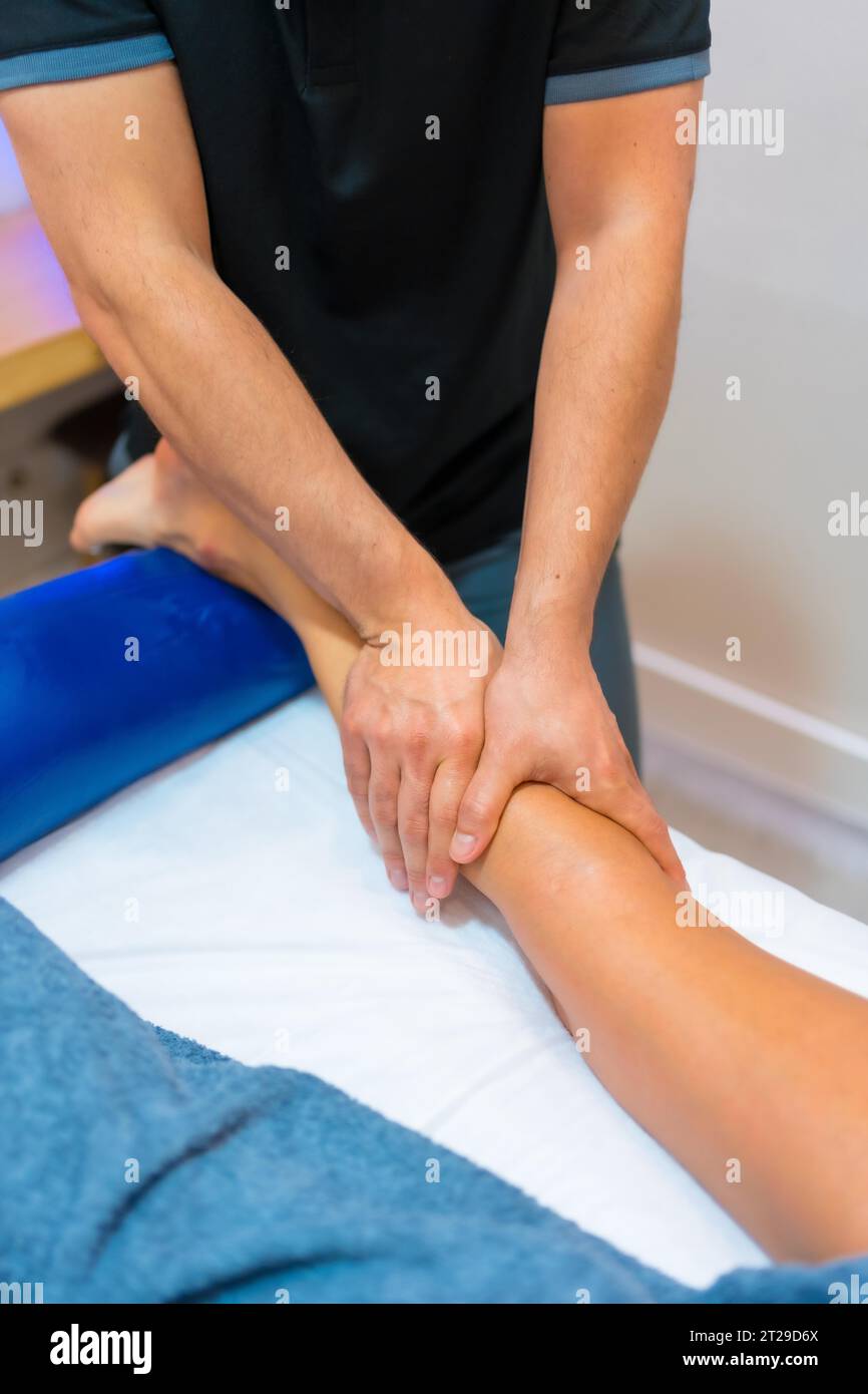 Physiotherapeutische Massage bei einer nicht erkennbaren Frau, die auf einer Beintrage liegt Stockfoto