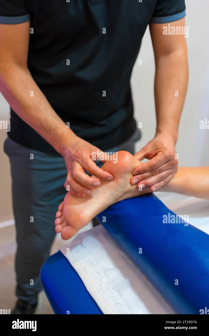 Physiotherapeutische Massage bei einer nicht erkennbaren Frau, die auf einer Bahre am Fuß liegt Stockfoto