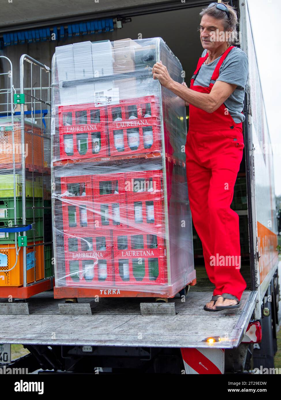 Mann auf Laderampe LKW, Lieferung mit Bio-Waren und Wasserkästen in Trolleys, Versorgung Einzelhandel und Transport Bio-Handel, Deutschland Stockfoto