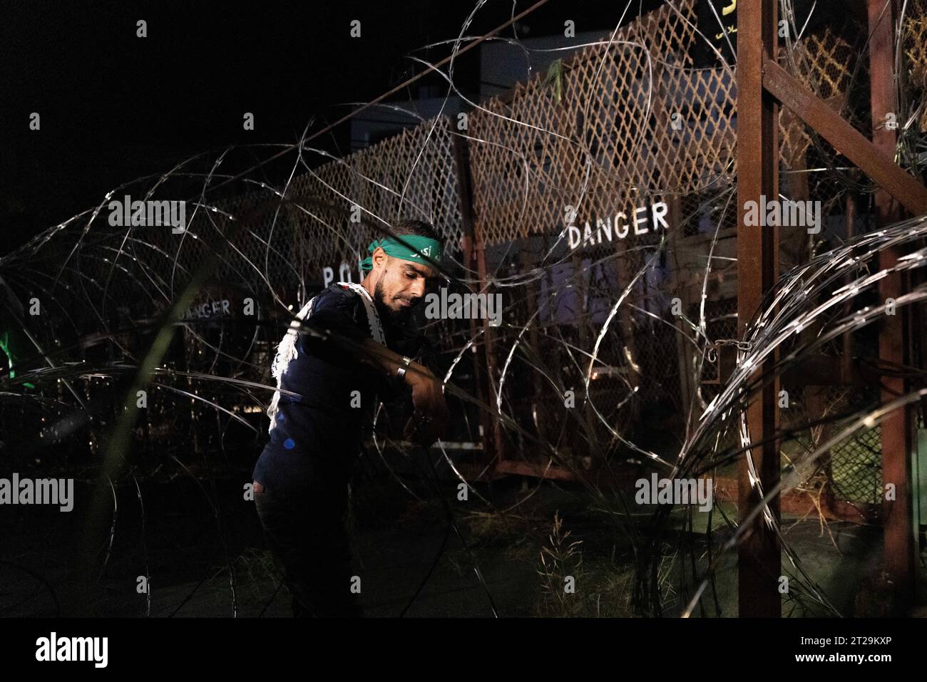 Awkar, Libanon. Oktober 2023. Ein Demonstrant schiebt sich während eines Protestes in der Nähe der US-Botschaft in Awkar, Libanon, am frühen Morgen des 18. Oktober 2023 durch Stacheldraht. Menschen protestierten gegen den israelischen Streik im Al-Ahli Baptist Hospital und töteten rund 500 Menschen in Gaza. Mehrere Verletzungen ereigneten sich, als die Anti-Aufruhr-Polizei einen Wasserkanone benutzte und Tränengas auf die Demonstranten schoss, wobei sie manchmal direkt auf die Demonstranten schrie, anstatt hoch in die Luft zu zielen, sodass die Kanister auf die Demonstration herunterfallen. (Kreditbild: © Daniel Carde/ZUMA Press Wire) NUR REDAKTIONELLE VERWENDUNG! Nicht Stockfoto