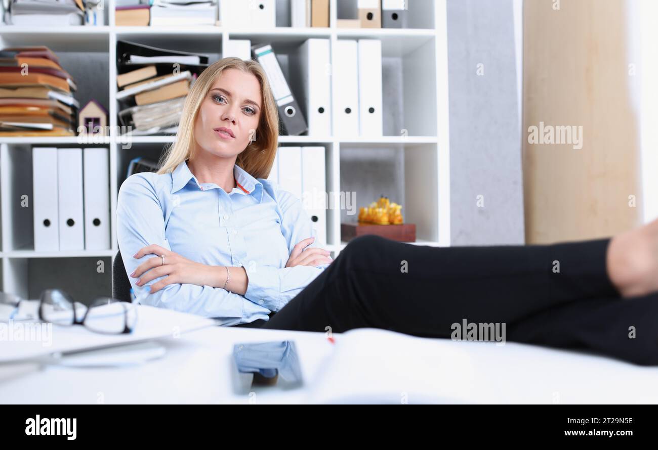 Business Frau Ruhe im Büro nach einem Arbeitstag die Füße werfen auf den Tisch lehnte sich zurück ihre Hände hinter dem Kopf Stockfoto