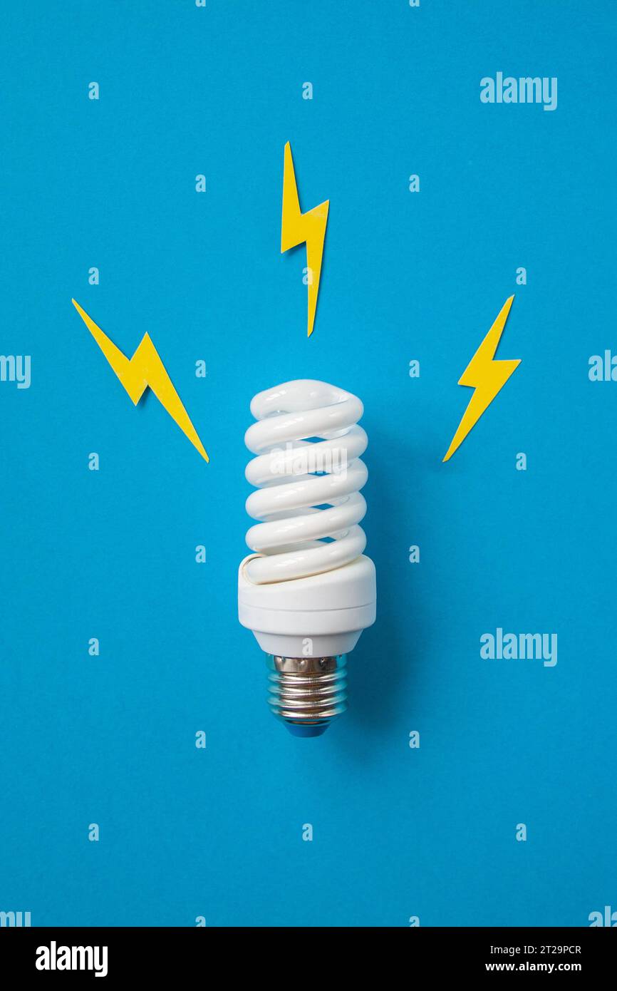 Glühlampe mit Energiebeleuchtung auf blauem Hintergrund Stockfoto