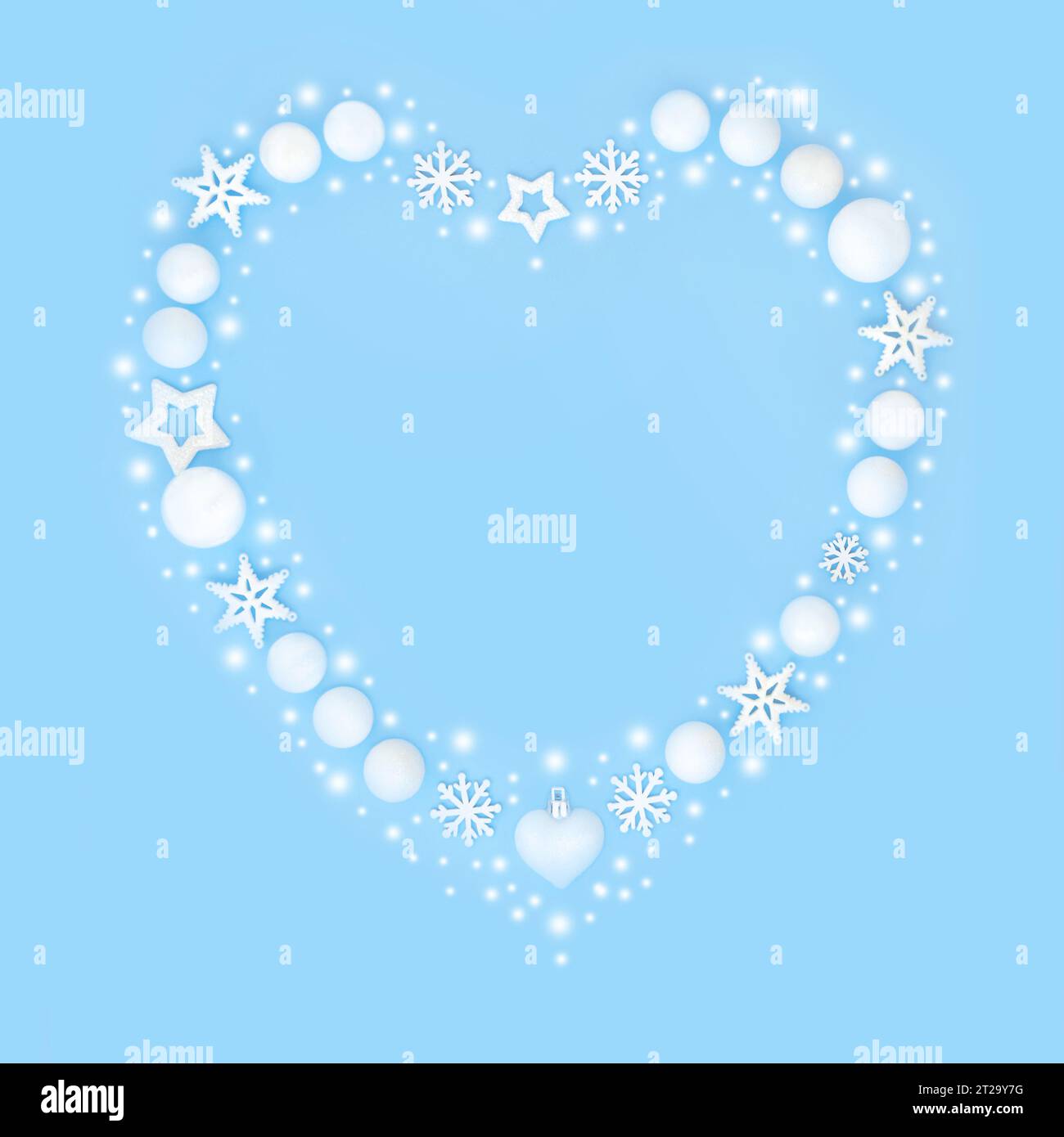 Weihnachtskranz in Herzform mit weißen Schneeflocken und Kugeln. Symbol für die Weihnachtszeit auf blauem Hintergrund. Stockfoto