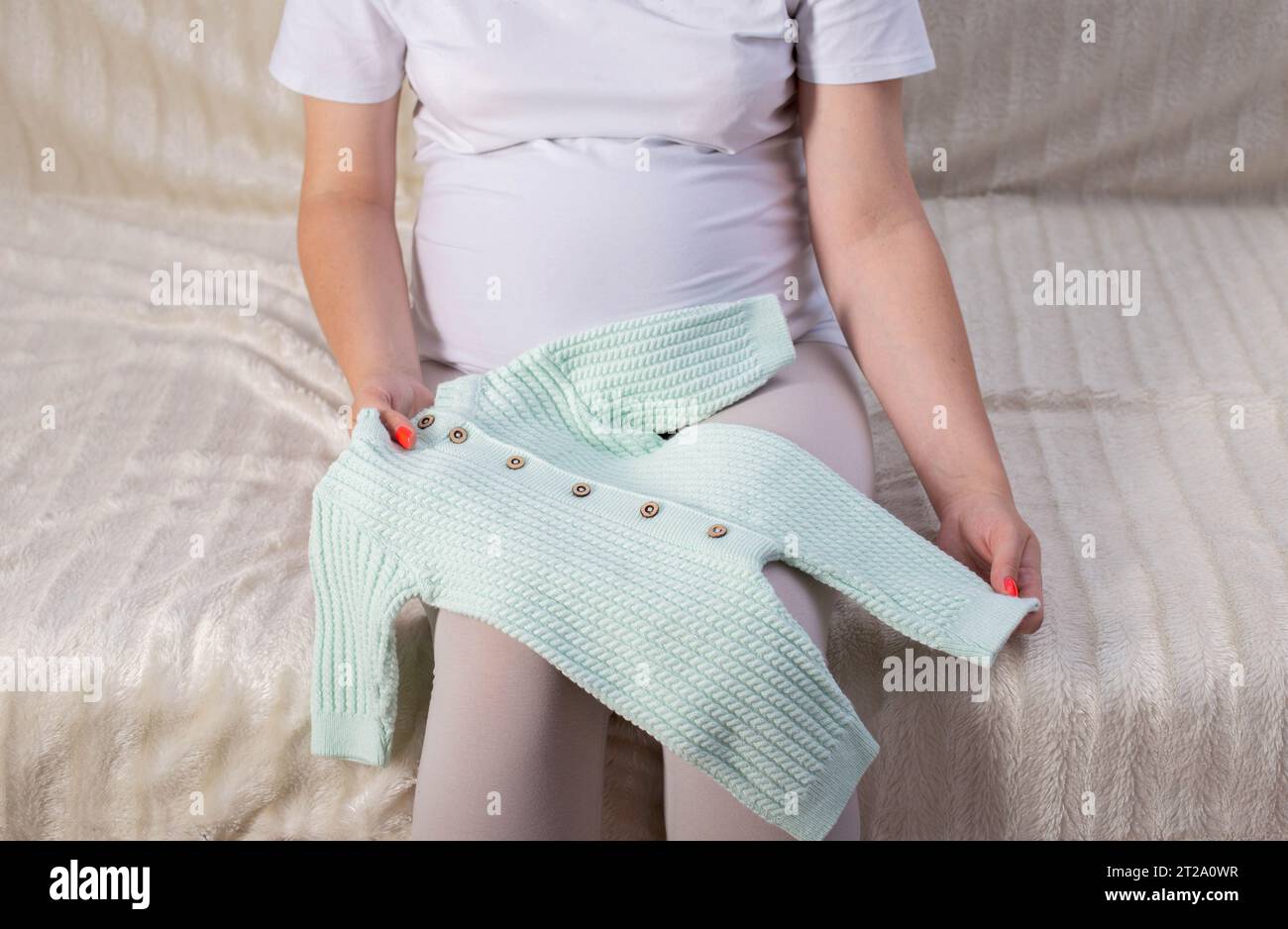 Ein schwangeres Mädchen sammelt Kleidung für ein Neugeborenes in der Entbindungsklinik. Stockfoto