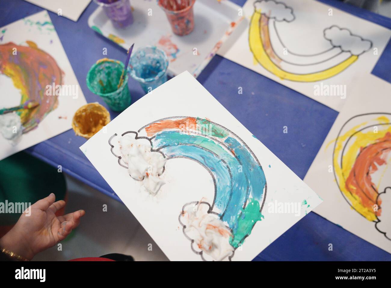 Kinder malen einen Regenbogen mit Pufffarben. Kinder färben sich im Klassenzimmer mit Pufffarben. Stockfoto