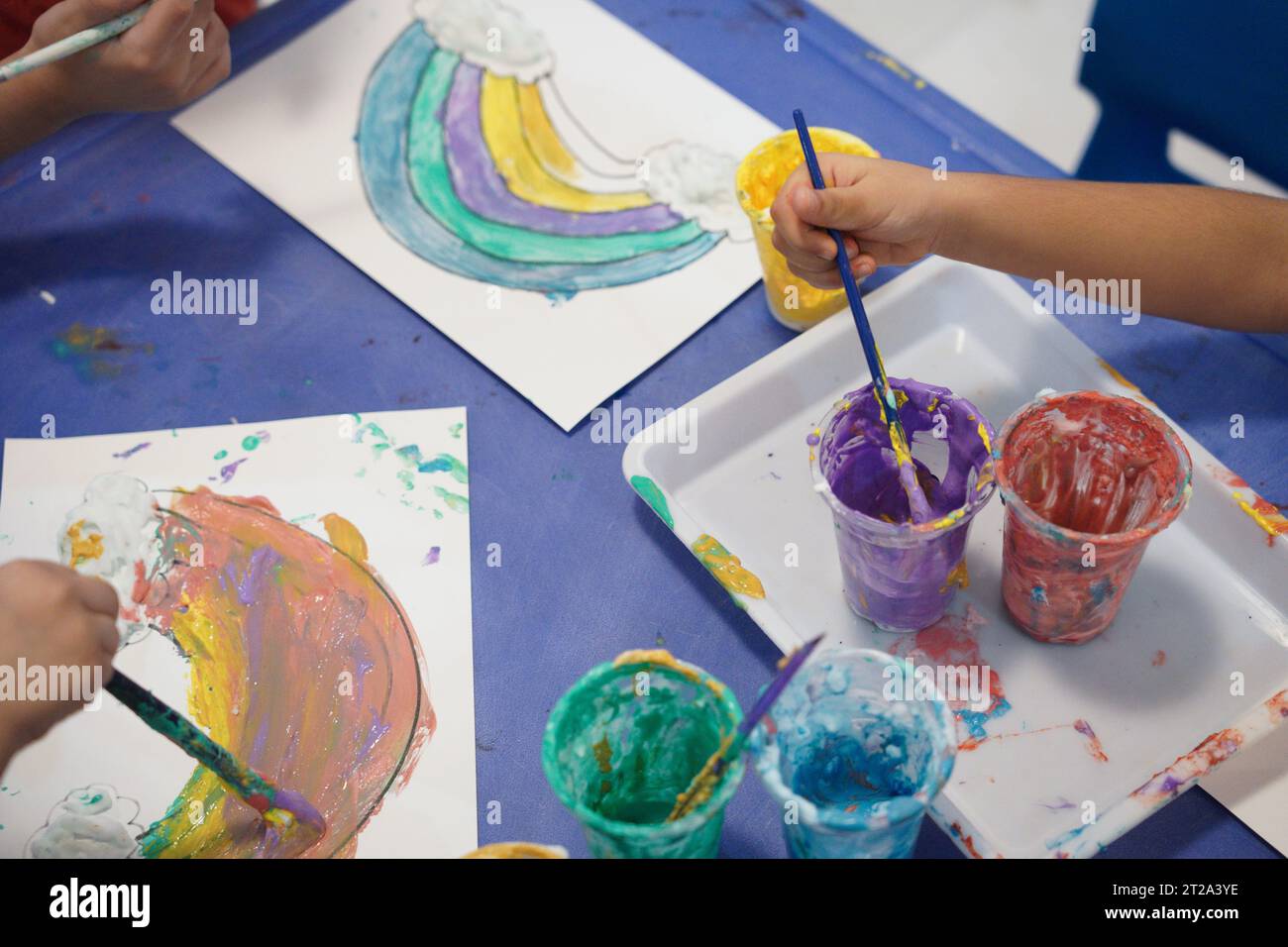 Kinder malen einen Regenbogen mit Pufffarben. Kinder färben sich im Klassenzimmer mit Pufffarben. Stockfoto