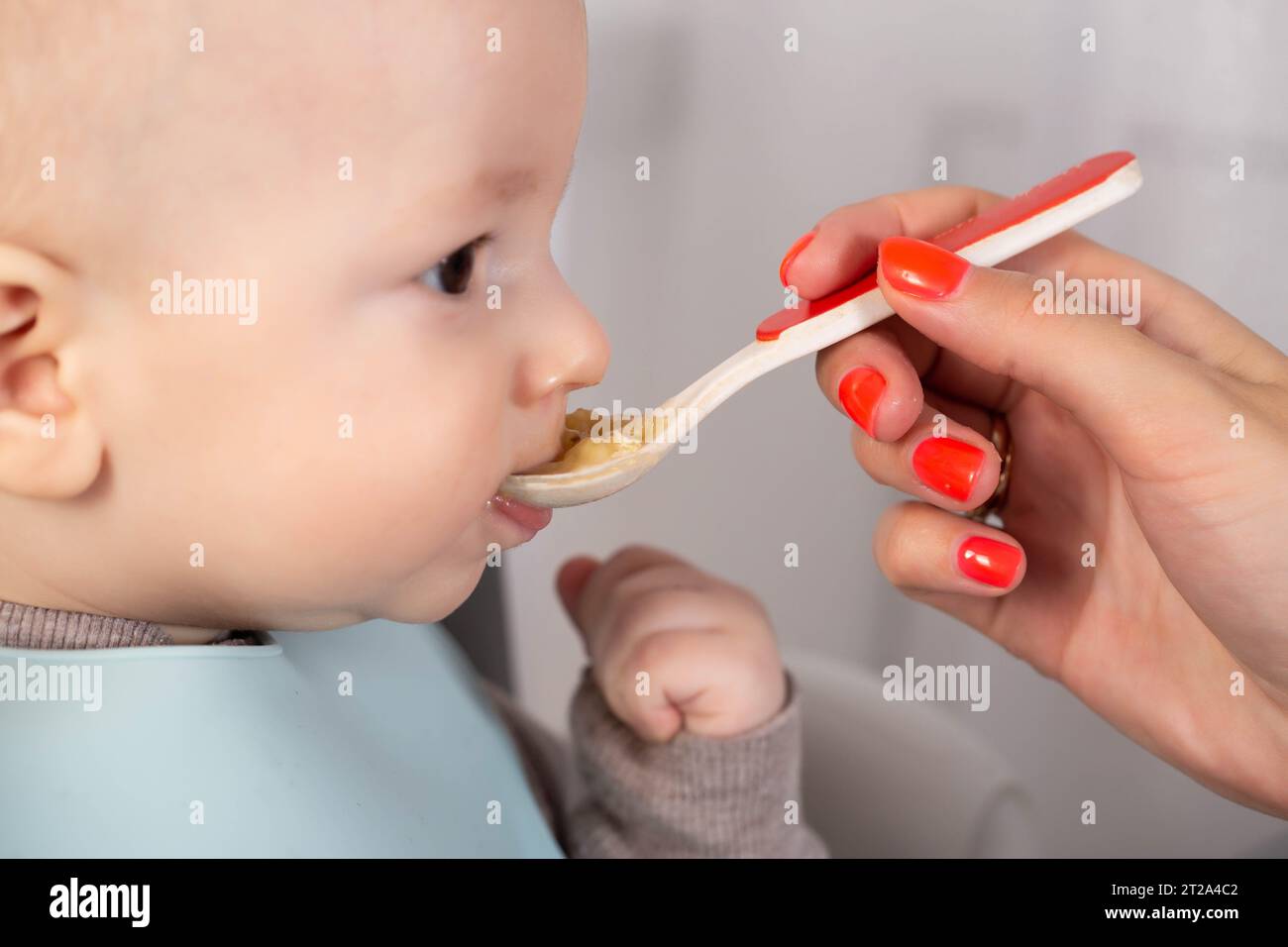 Die erste Fütterung mit Fruchtpüree für einen 6 Monate alten Jungen. Stockfoto