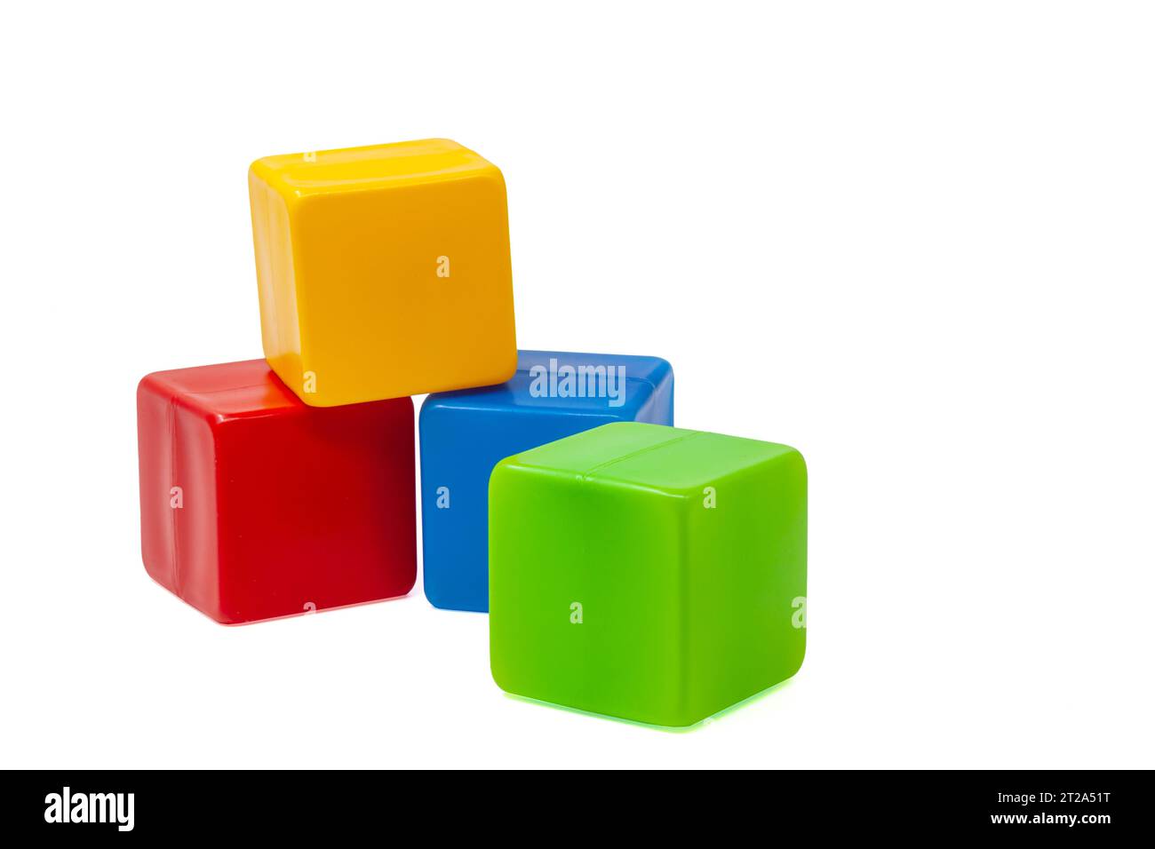 Mehrfarbige Plastikwürfel für Kinderspiele. Der gelbe Würfel steht oben auf dem roten und blauen Würfel, der grüne Würfel daneben. Eins auf eins. Hohe Qualität Stockfoto