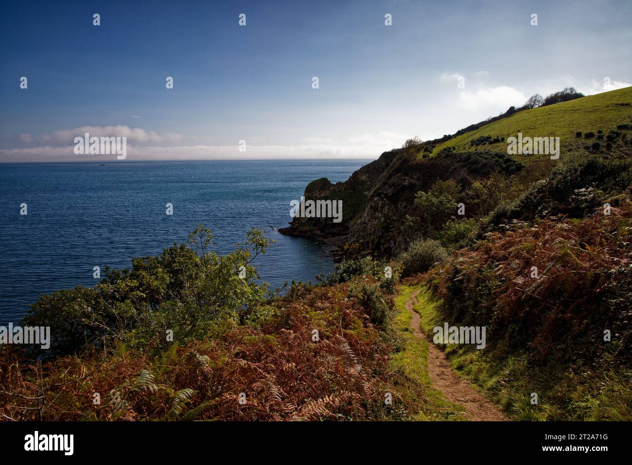 Der SW Coast Path folgt einer felsigen Küste mit blauem Meer und steilen Klippen bei Porthpean, Cornwall. Stockfoto