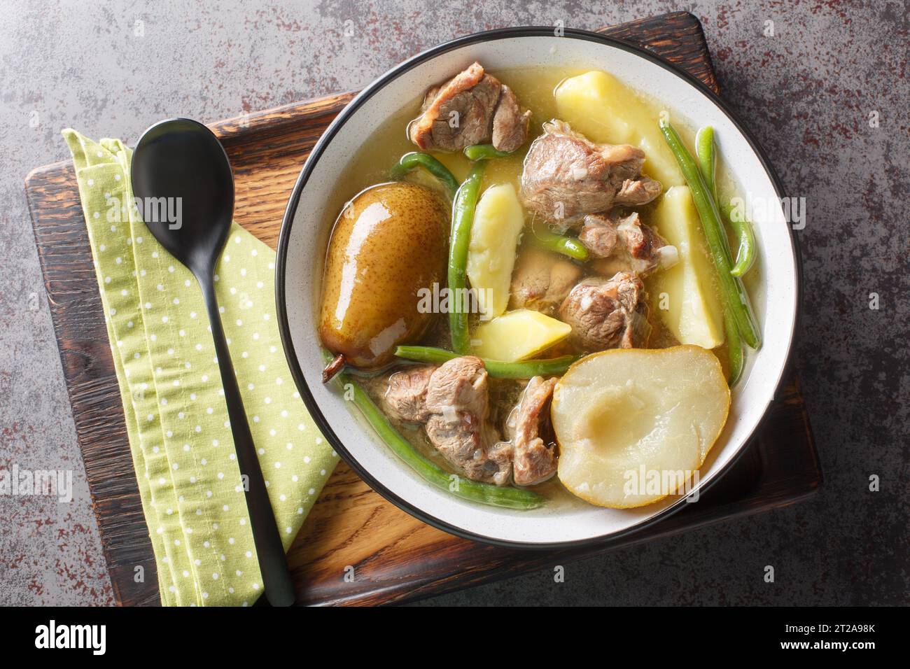 Hammelragout mit Birnen, Kartoffeln, Zwiebeln und grünen Bohnen auf dem Teller auf dem Tisch. Horizontale Draufsicht von oben Stockfoto