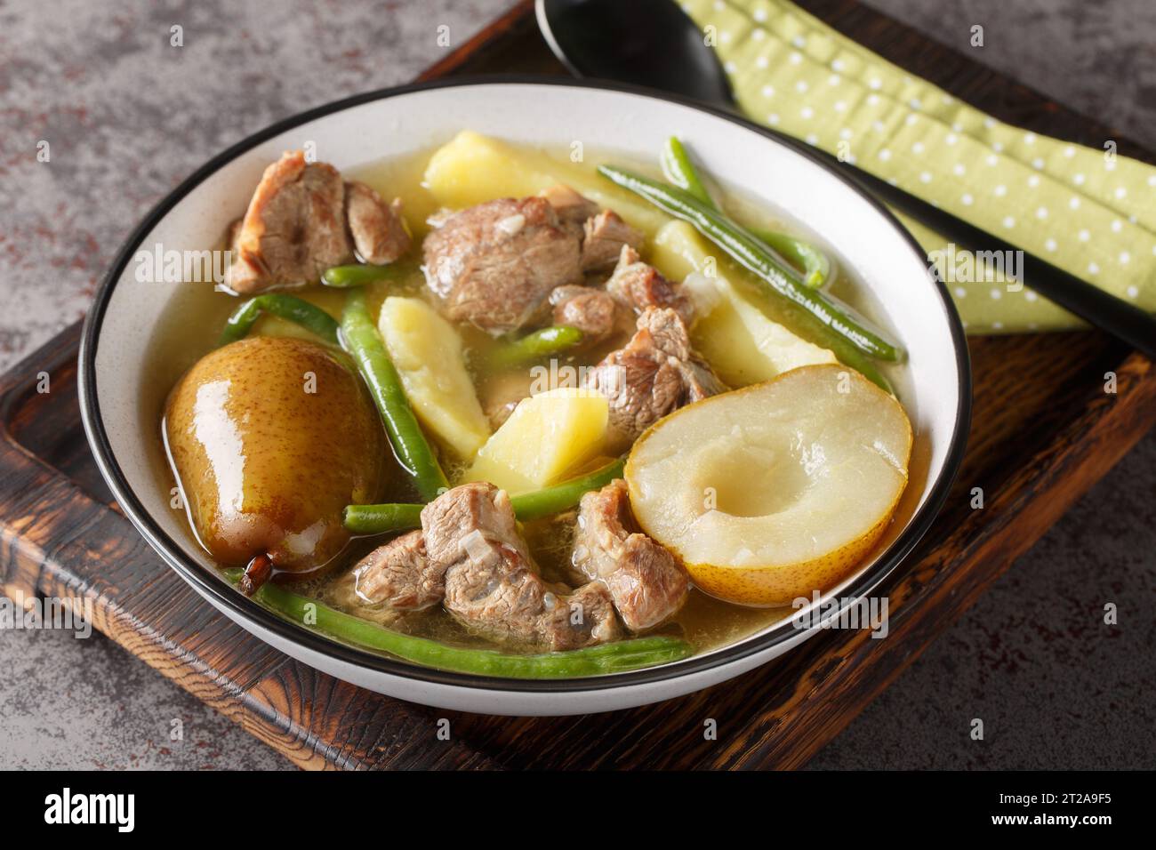 Schwedischer Lammeintopf mit frischen Birnen, Kartoffeln, grünen Bohnen in einer Schüssel auf einem Holzbrett. Horizontal Stockfoto