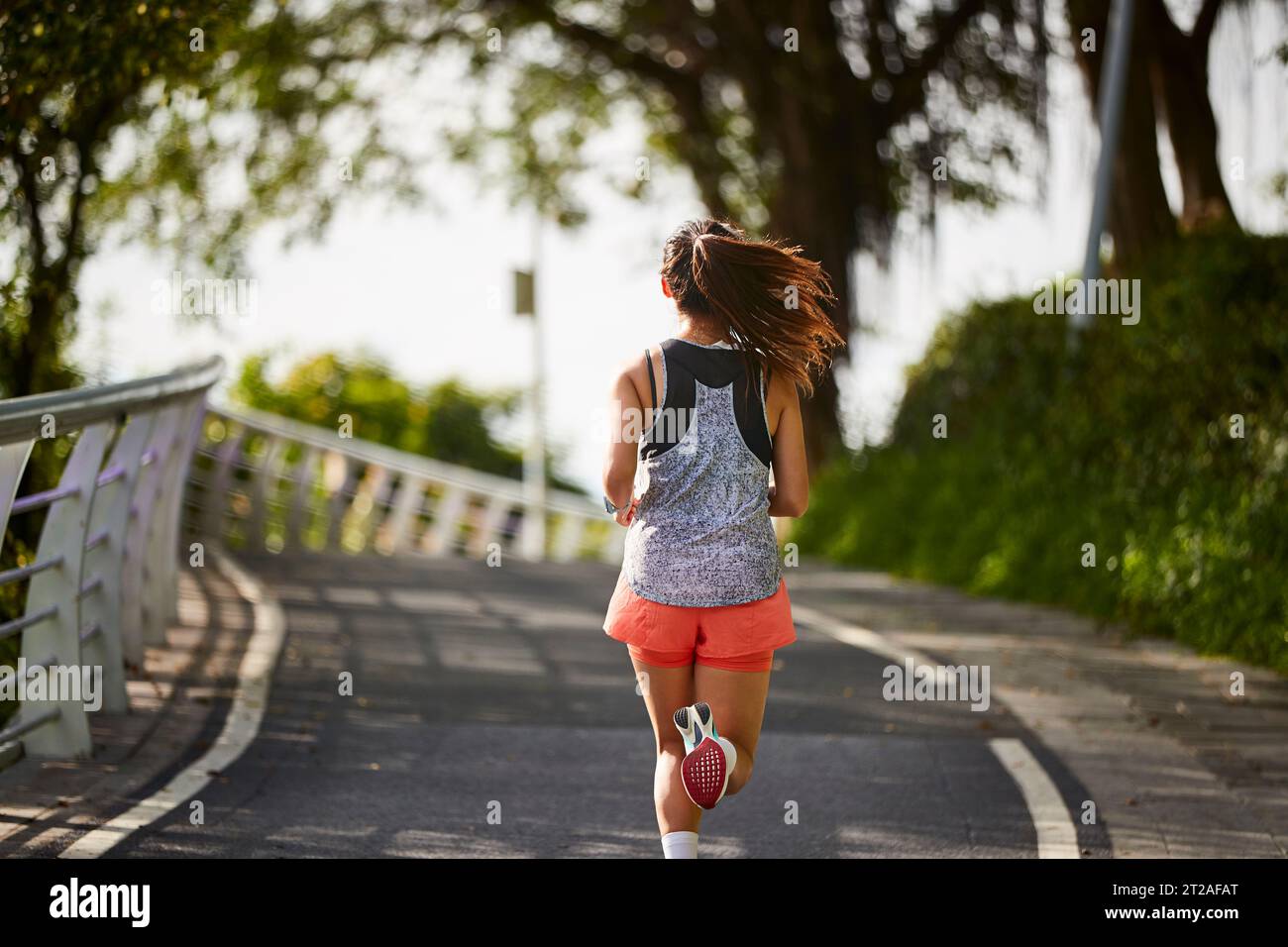 Rückansicht einer jungen asiatischen Frau, die draußen im Park joggt Stockfoto
