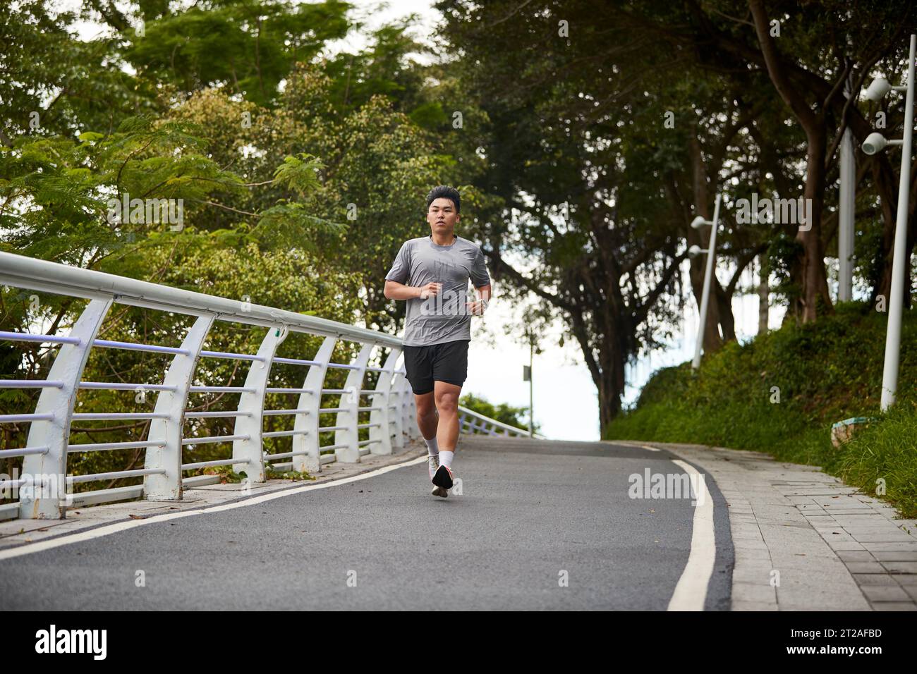 Junger asiatischer Mann, der draußen im Park joggt Stockfoto