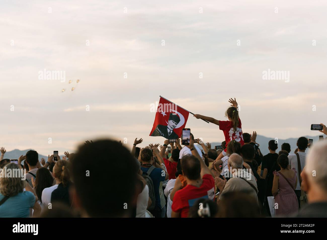 Izmir, Türkei, 9. September 2023, in einem Meer von Zuschauern schwingt ein junges Mädchen auf jemandem Schultern stolz eine türkische Flagge, die Atatürks trägt Stockfoto