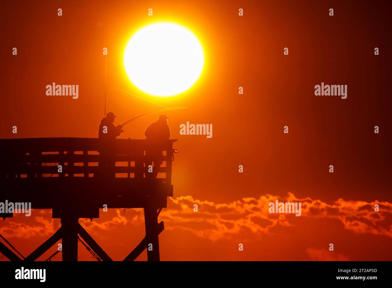 Isle Of Palms, Usa. 17. Oktober 2023. Fisherman Silhouetted by the Sunrise Probieren Sie ihr Glück am Isle of Palms Pier, 17. Oktober 2023 in Isle of Palms, South Carolina. Quelle: Richard Ellis/Richard Ellis/Alamy Live News Stockfoto