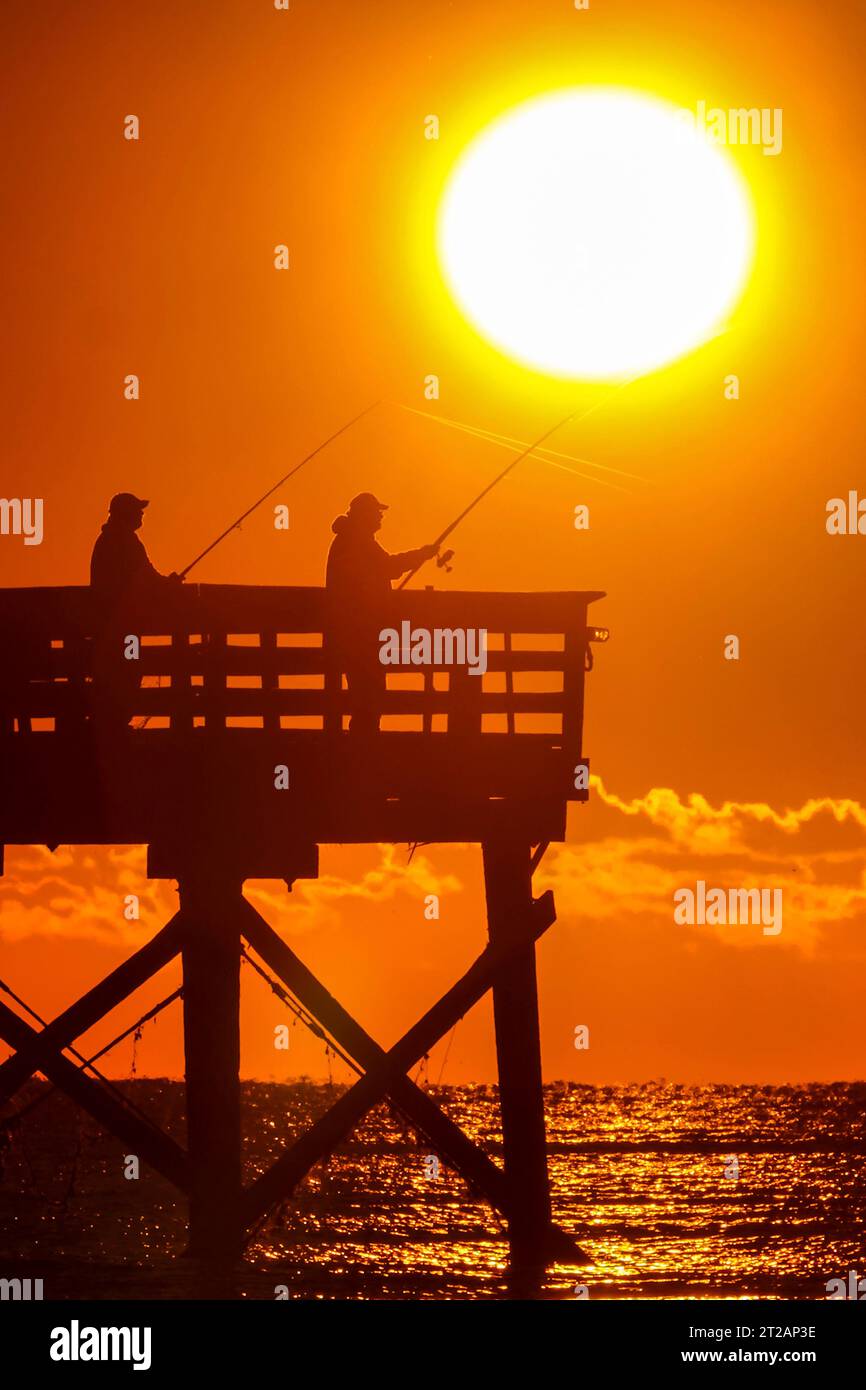 Isle Of Palms, Usa. 17. Oktober 2023. Fisherman Silhouetted by the Sunrise Probieren Sie ihr Glück am Isle of Palms Pier, 17. Oktober 2023 in Isle of Palms, South Carolina. Quelle: Richard Ellis/Richard Ellis/Alamy Live News Stockfoto