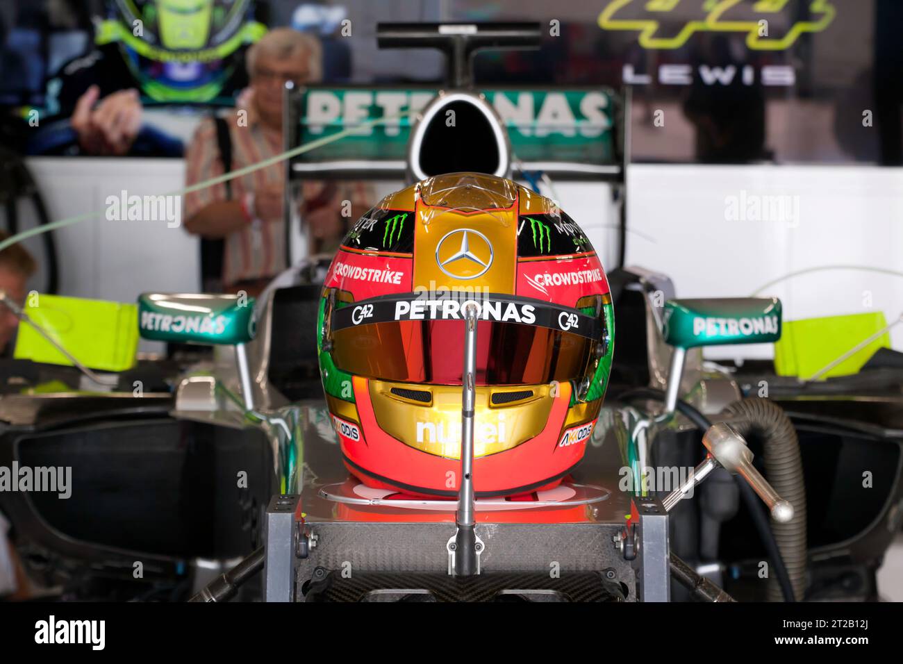 Nahaufnahme von Lewis Hamiltons Rennhelm, der auf seinem Mercedes Petronas Formel-1-Wagen sitzt und in einer internationalen Boxengarage ausgestellt ist. Stockfoto