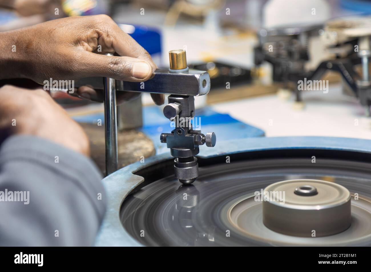 Hand eines Mannes afrikanischer Arbeiter, der einen Diamanten in der Fabrik am Spinnrad poliert Stockfoto
