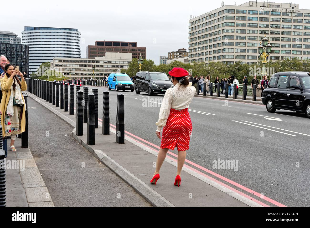 Rückansicht einer attraktiven asiatischen Frau mit rotem Hut und Rock, die auf der Westminster Bridge für ein Touristenfoto posiert, Central London England UK Stockfoto