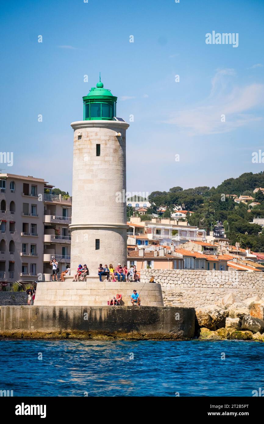 Die Menschen entspannen sich am Fuße des Leuchtturms von Cassis, der an der Mündung des Hafens von Cassis in Südfrankreich steht. Stockfoto