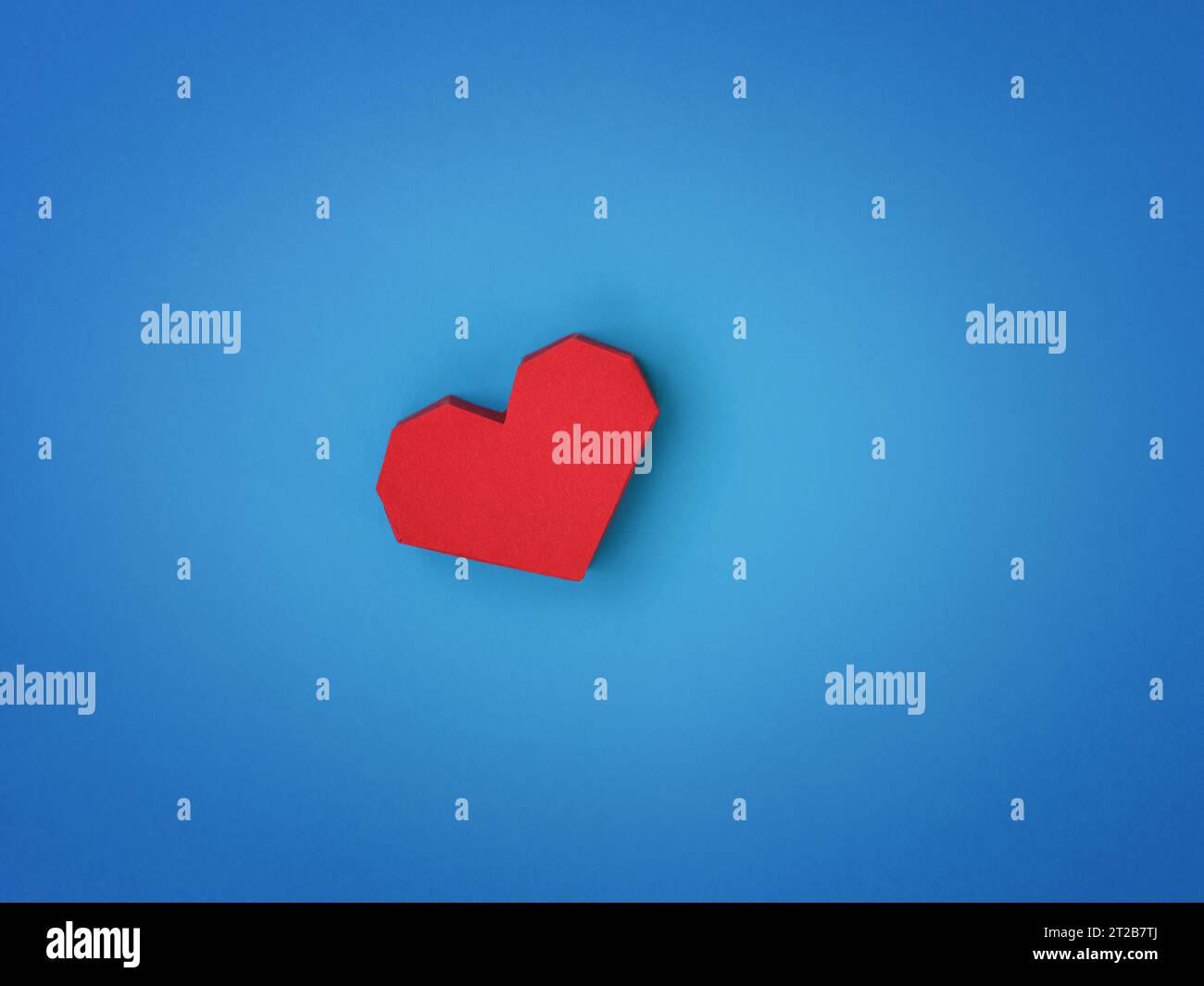 Ein rotes Papierherz auf blauem Papierhintergrund. Nahaufnahme. Stockfoto