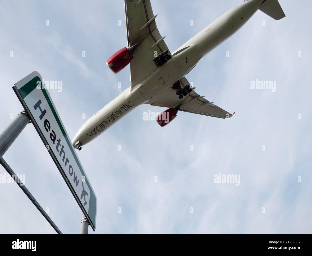 London Heathrow Airport Hounslow, Straßenschild für den Flughafen Heathrow mit Virgin Atlantic Airbus A350-1041 tief fliegendes Flugzeug über dem Himmel Stockfoto