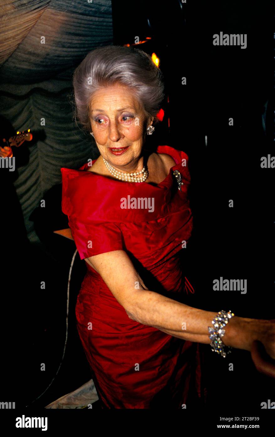 Wohlhabende ältere, mit Juwelen geschmückte Dame mit Edelsteinen, Diamanten und Armband und Perlenkette. Sie ließ sich wahrscheinlich an dem Nachmittag Haare machen. Gestylt wie Prinzessin Anne in einen geschwollenen Bouffant, der in einen französischen Faltenfrisur gewickelt wird. Trägt ein rotes Ballkleid und einen roten Lippenstift. Dinner Dance im Tysoe Manor, Tysoe, Warwickshire, England April 1982. HOMER SYKES AUS DEN 1980ER JAHREN. Stockfoto