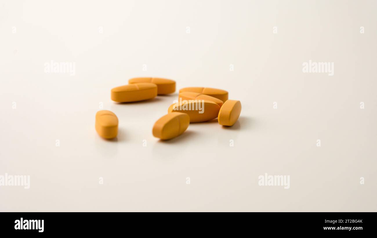 Multivitamin-Ergänzungspillen vor einem neutralen cremeweißen Hintergrund. Stockfoto