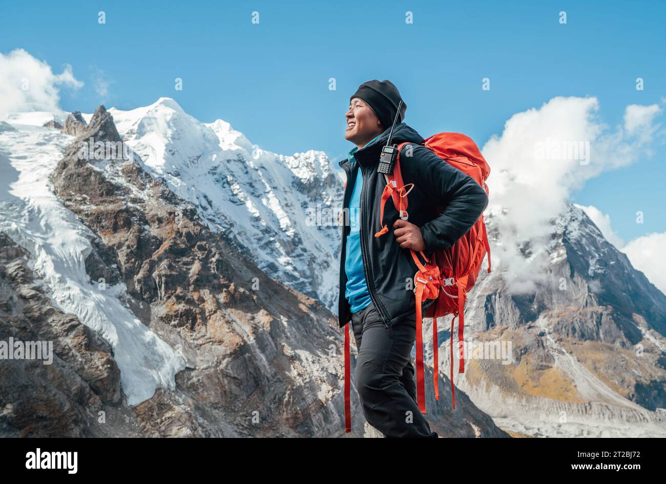Porträt eines lächelnden Sherpa-Mannes mit Rucksack und Blick auf die Berge und die frische Luft mit dem 6476 m hohen Mera-Gipfel. Himalaya-Expedition während m Stockfoto