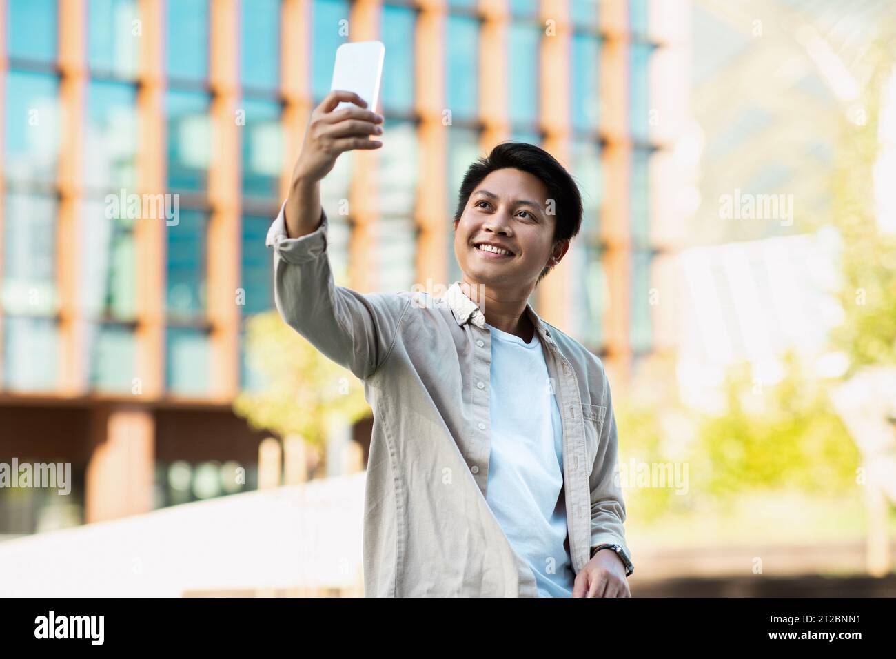 Fröhlicher junger asiatischer Unternehmer, der Selfie auf der Straße macht Stockfoto