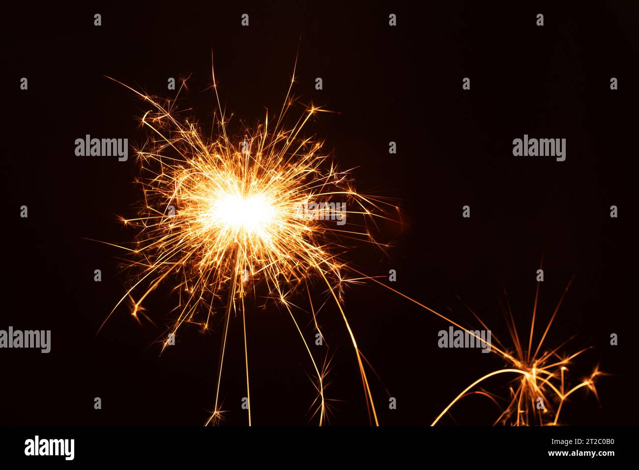 Foto auf diesem Foto leuchtet ein heller Funkler, der den Weihnachtsgeist des Neujahrs erleuchtet. Die Nahaufnahme zeigt die feurige Schönheit eines brennenden Balkens Stockfoto