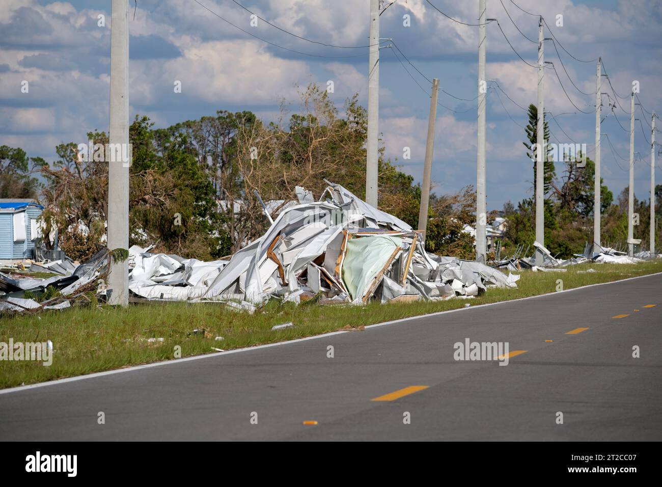 Müllhaufen auf der Straßenseite von stark beschädigten Häusern nach dem Hurrikan in Florida Wohnmobilgebiet. Folgen von Naturkatastrophen Stockfoto