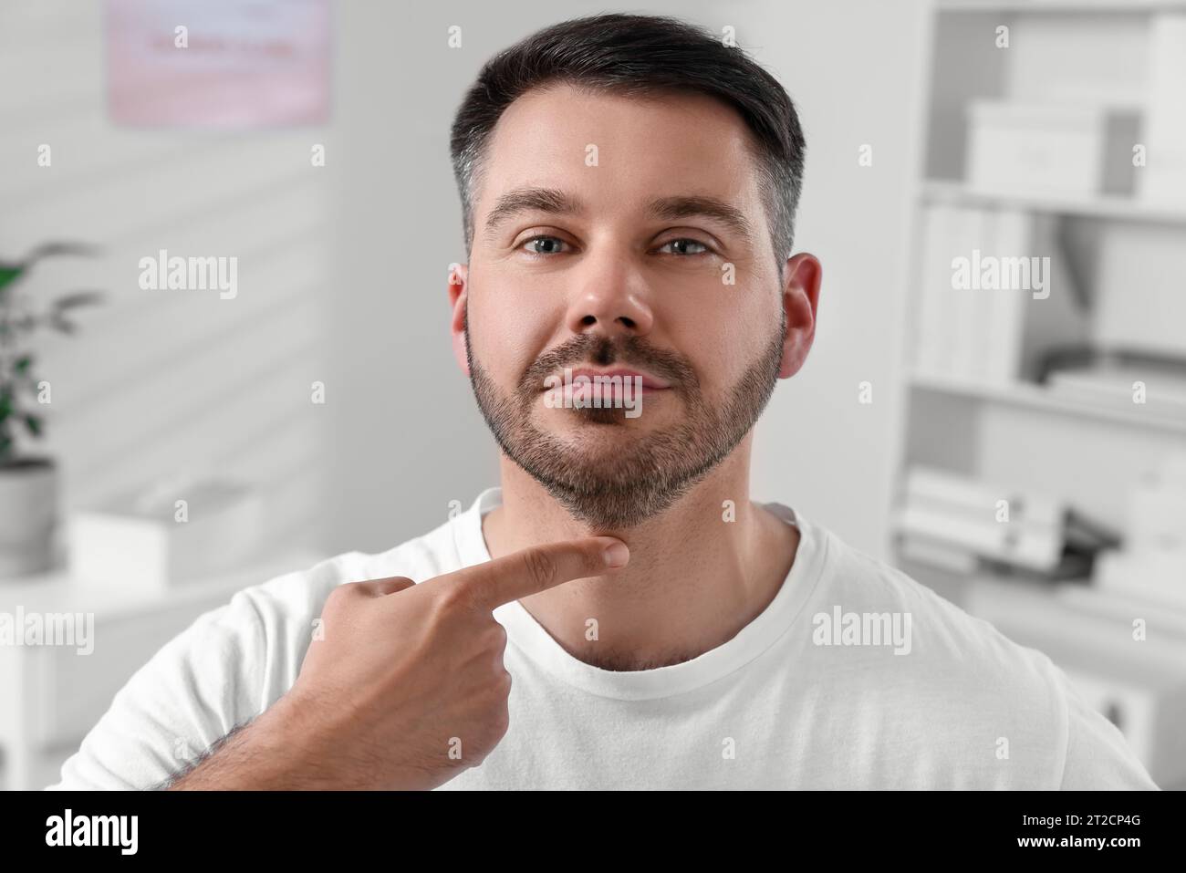 Endokrines System. Ein Mann, der sich drinnen einer Schilddrüsen-Selbstuntersuchung unterzieht Stockfoto