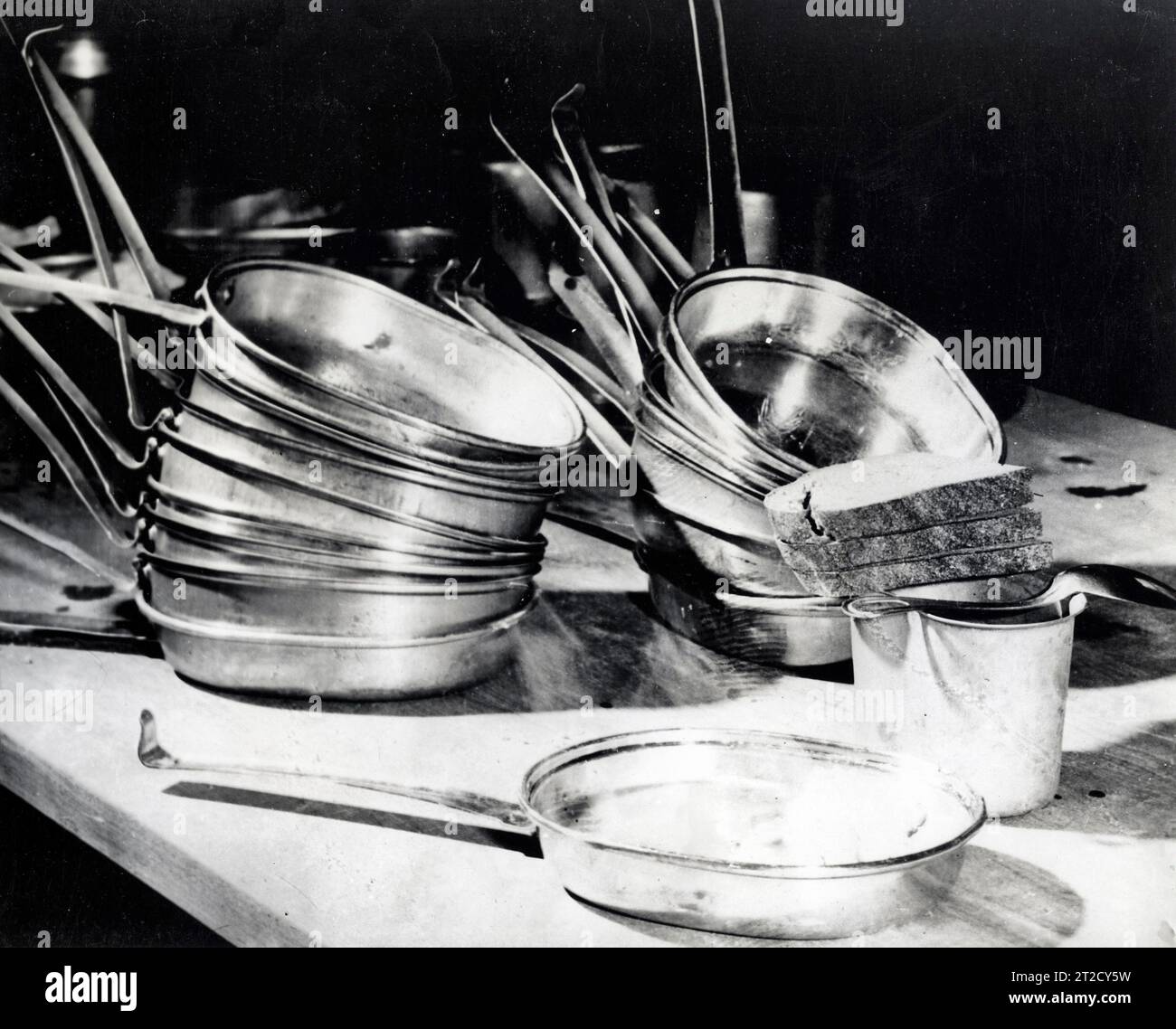 Mittagessen für Göring; im Vordergrund steht ein Mittagessen, das zum ehemaligen Chef der Luftwaffe gebracht werden kann. Es besteht aus drei Brotstücken (ca. 150 Gramm), einer Tasse (und nur einer) Kaffee, etwa 200 Gramm dehydrierten Eiern und einem Gulasch (Eintopf) von etwa 200 Gramm. Die Essausstattung besteht aus einem Löffel, einer Kantinenschale ohne Griff und einer GI-Fleischdose. Im Hintergrund stehen die Mess-Kits für andere Gefangene, die vor dem Internationalen Militärtribunal in Nürnberg vor Gericht stehen Stockfoto