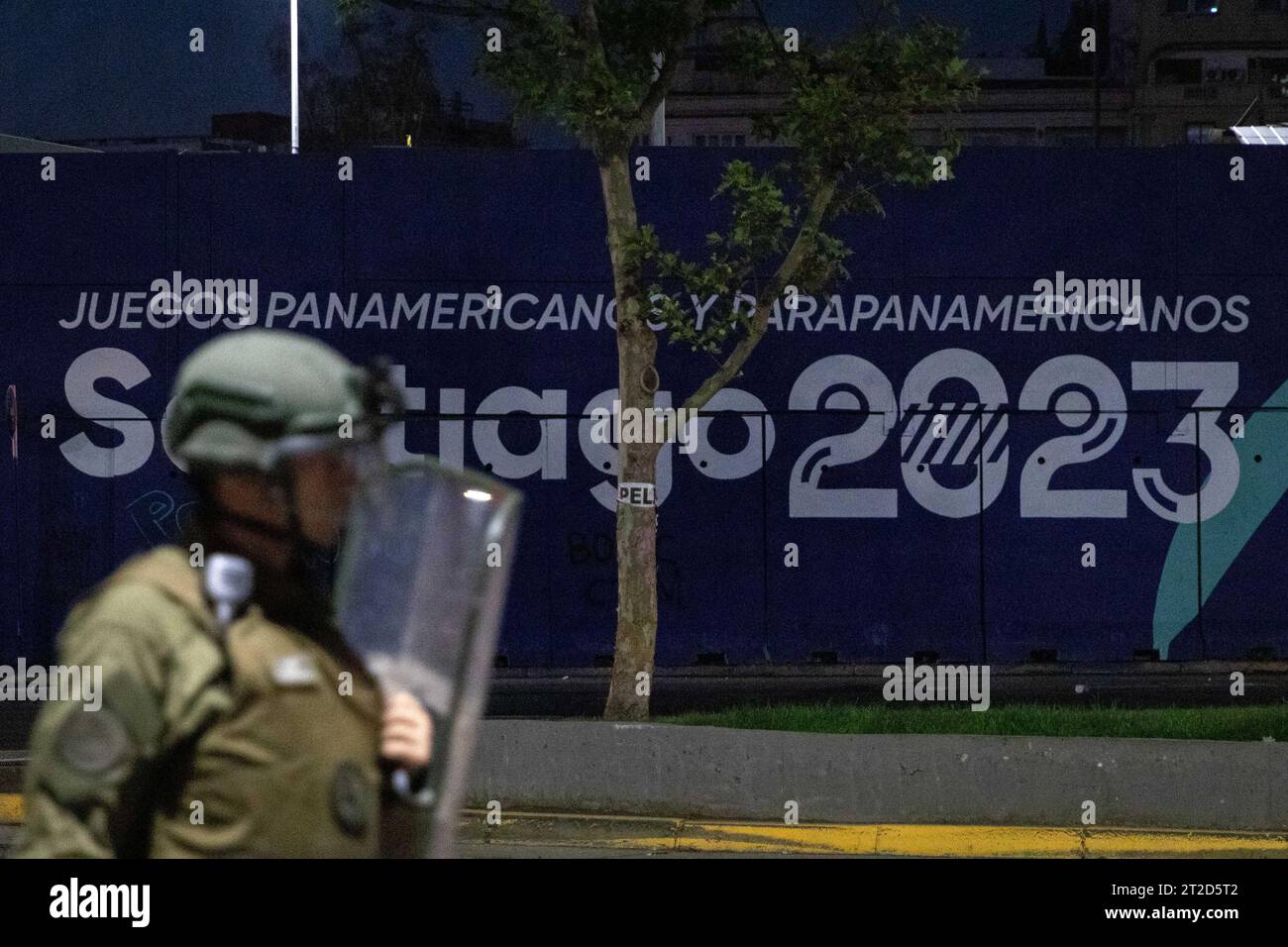 Santiago, Metropolregion, Chile. Oktober 2023. Ein Anti-Rebellion-Offizier von Carabineros vor einer Werbetafel, die die Pan American Games 2023 in Santiago, Chile, während des vierten Jahrestages der Anti-Regierungs-Proteste, am 18. Oktober 2023, anwarb. Die XIX Panamerikanischen Spiele finden am 20. Oktober in Santiago statt. (Kreditbild: © Joshua Arguello/ZUMA Press Wire) NUR REDAKTIONELLE VERWENDUNG! Nicht für kommerzielle ZWECKE! Stockfoto